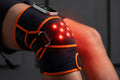 Rodillera de terapia de luz roja Llunea puesta en rodilla con LEDs 660nm y 850nm encendidos